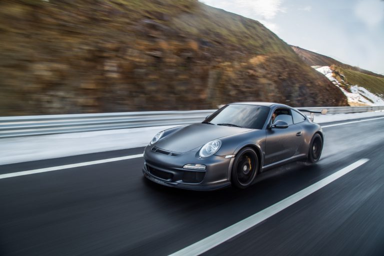 Mini coupe driving on the highway across mountains