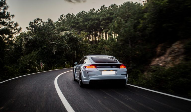 fast car driving on a road with trees in the distance
